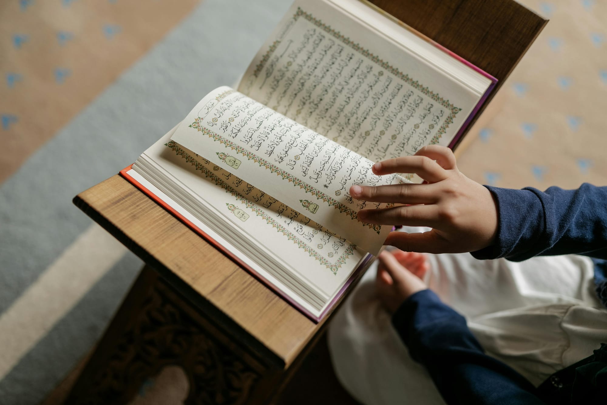 A photo of a hand turning the page of a Quran.